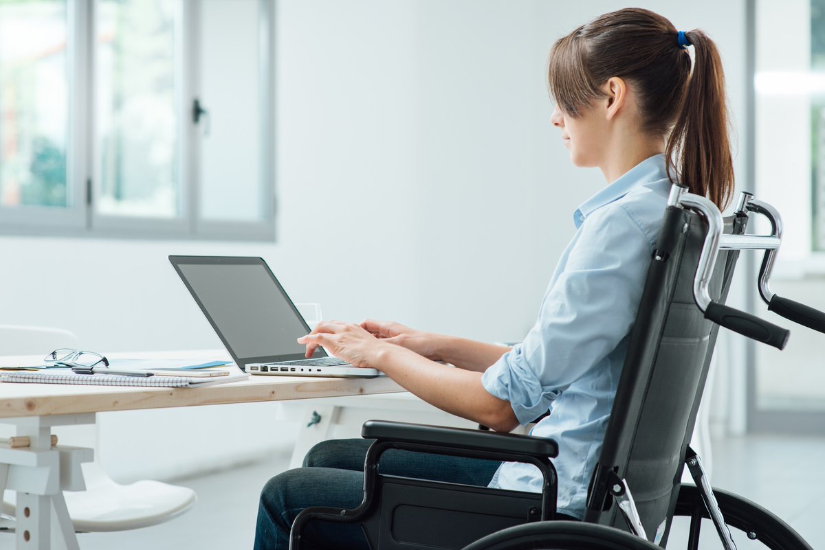 imagen de una mujer escribiendo en el ordenador en una silla de ruedas
