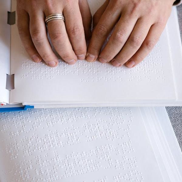 imagen de las manos de una persona leyendo un documento braille