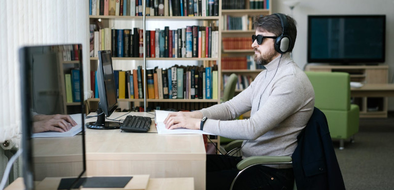 imagen de una persona leyendo en braille dentro de un espacio cerrado, presumiblemente una biblioteca